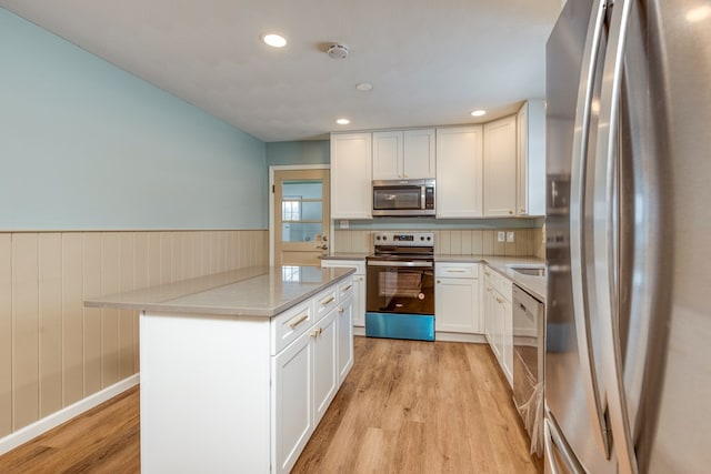 867 NE Wayne Ave, Abingdon, VA 24210 - kitchen with stainless steel appliances, light wood-type flooring, white cabinetry, a wainscoted wall, and a center island