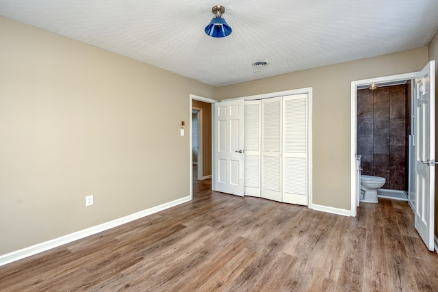 867 NE Wayne Ave, Abingdon, VA 24210 - unfurnished bedroom featuring a closet, wood finished floors, and ensuite bath