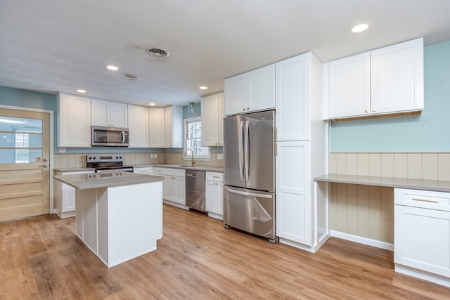 867 NE Wayne Ave, Abingdon, VA 24210 - kitchen featuring appliances with stainless steel finishes, light countertops, white cabinets, light wood finished floors, and a wainscoted wall