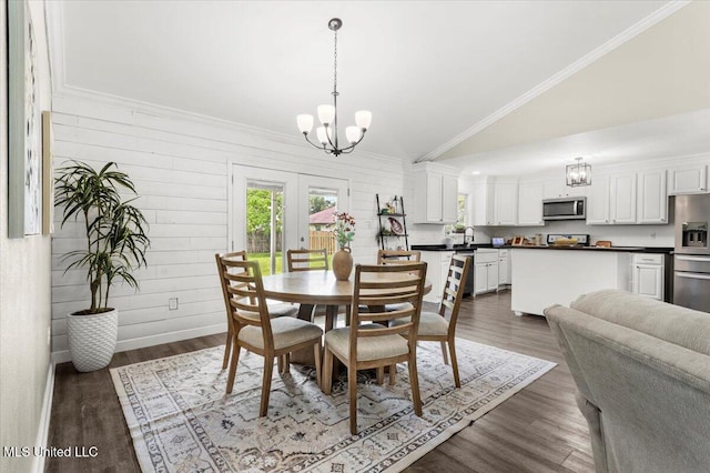 10601 W River Vue, Biloxi, MS 39532 - dining space featuring lofted ceiling, a chandelier, dark wood-style flooring, crown molding, and wooden walls