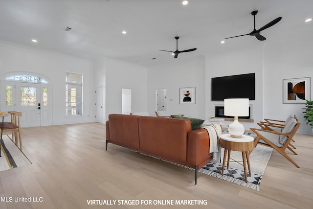 living room with ceiling fan, ornamental molding, and light wood-type flooring