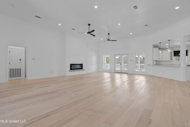 unfurnished living room with ornamental molding, a high ceiling, light hardwood / wood-style floors, and ceiling fan