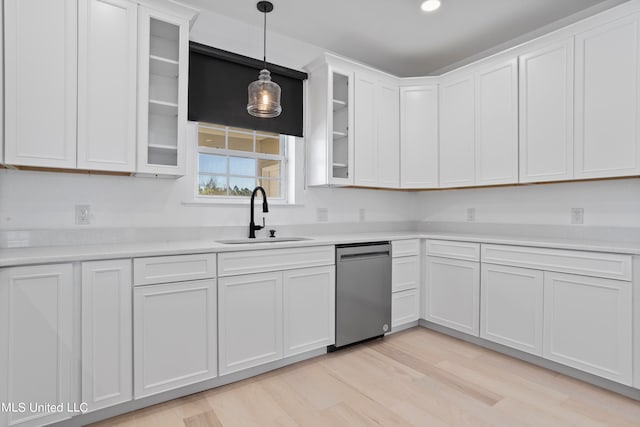 kitchen featuring dishwasher, light hardwood / wood-style flooring, sink, decorative light fixtures, and white cabinets