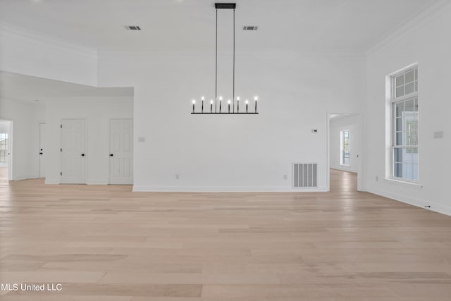 unfurnished living room with ornamental molding, a high ceiling, light hardwood / wood-style flooring, and a notable chandelier