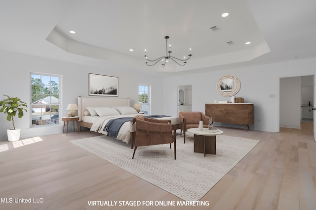 bedroom featuring a chandelier, a tray ceiling, and light hardwood / wood-style floors