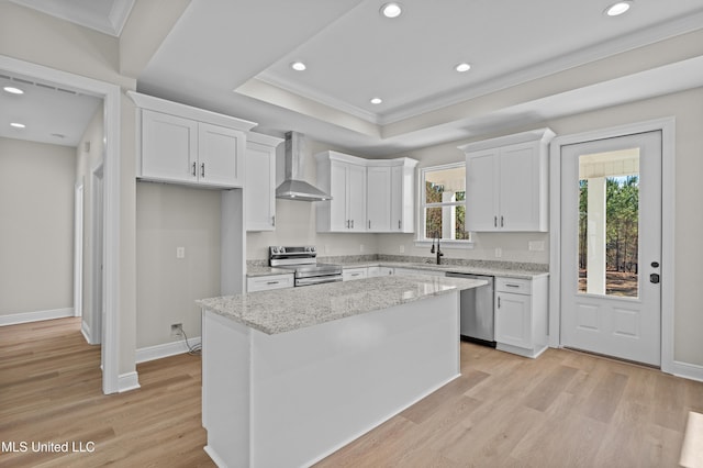 kitchen featuring white cabinets, wall chimney exhaust hood, a kitchen island, and stainless steel appliances