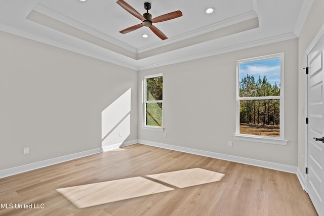 empty room featuring a tray ceiling, ceiling fan, light hardwood / wood-style floors, and ornamental molding