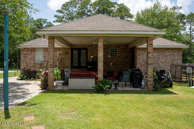6816 Natchez St, Biloxi, MS 39532 - rear view of house with a patio, brick siding, and roof with shingles