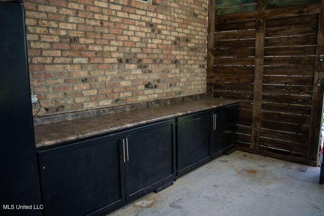 6816 Natchez St, Biloxi, MS 39532 - interior space featuring unfinished concrete flooring, brick wall, dark cabinets, and dark countertops