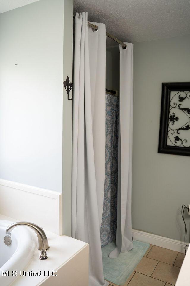 6816 Natchez St, Biloxi, MS 39532 - bathroom featuring tile patterned floors, a textured ceiling, and a shower with shower curtain