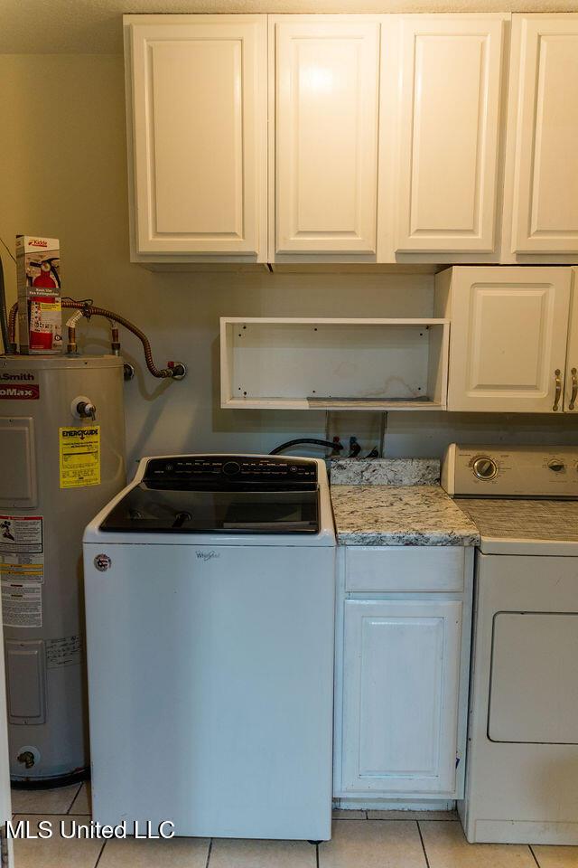 6816 Natchez St, Biloxi, MS 39532 - laundry area featuring washer / clothes dryer, water heater, cabinet space, and light tile patterned flooring