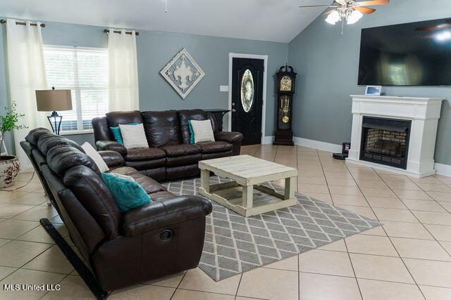 6816 Natchez St, Biloxi, MS 39532 - tiled living area with a ceiling fan, vaulted ceiling, and a fireplace