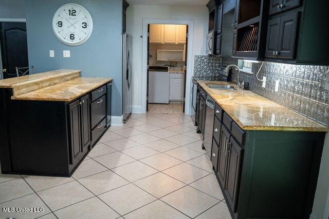 6816 Natchez St, Biloxi, MS 39532 - kitchen with freestanding refrigerator, light tile patterned floors, tasteful backsplash, dark cabinets, and a peninsula