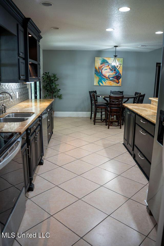 6816 Natchez St, Biloxi, MS 39532 - kitchen with appliances with stainless steel finishes, backsplash, dark cabinets, light stone countertops, and recessed lighting