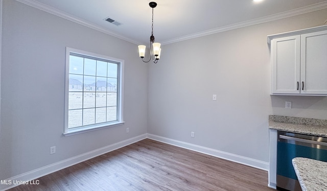 unfurnished dining area with visible vents, wood finished floors, crown molding, baseboards, and a chandelier