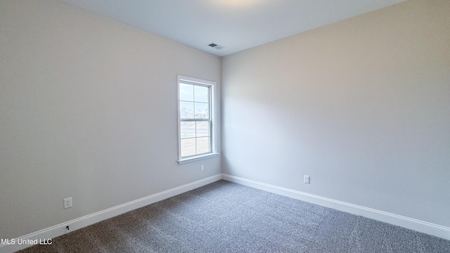 unfurnished room with visible vents, baseboards, and dark carpet