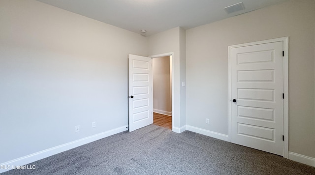 unfurnished bedroom with baseboards and dark carpet