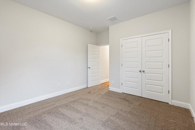 unfurnished bedroom with visible vents, baseboards, a closet, and carpet flooring