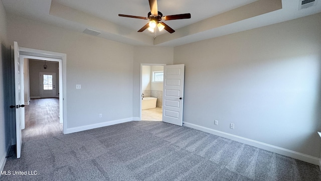 unfurnished bedroom featuring visible vents, baseboards, carpet, and a tray ceiling