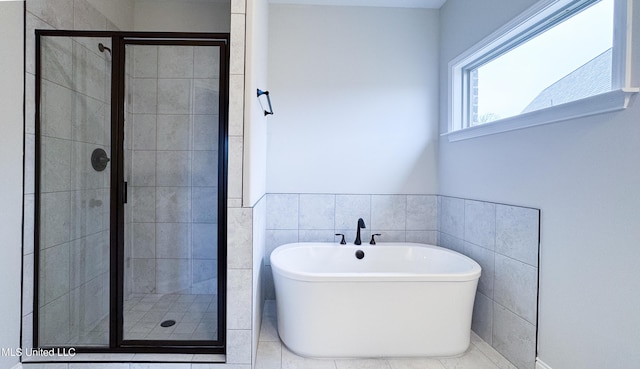 bathroom featuring a freestanding tub, tile walls, and a shower stall