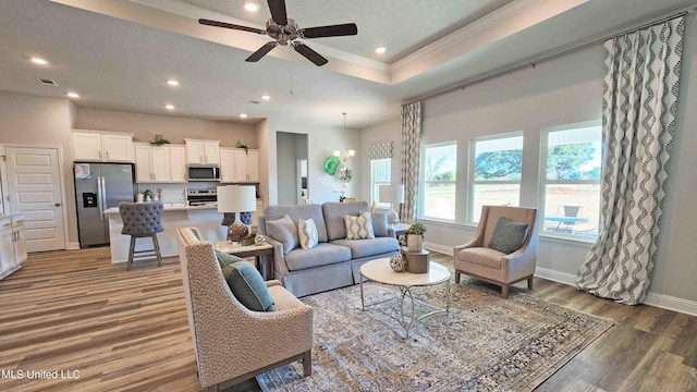 living room with a textured ceiling, dark wood-type flooring, ceiling fan with notable chandelier, and ornamental molding