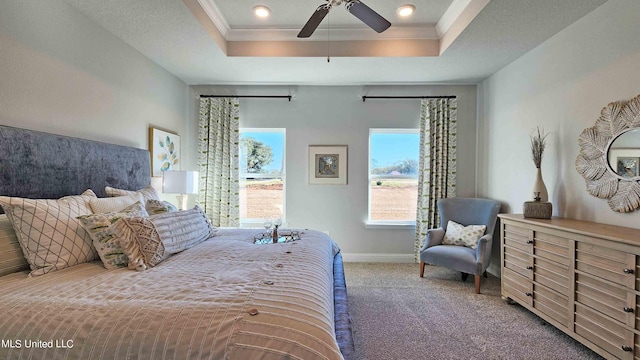 carpeted bedroom with a tray ceiling, ceiling fan, and crown molding