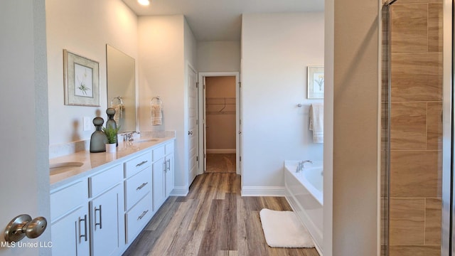 bathroom with a washtub, wood-type flooring, and vanity