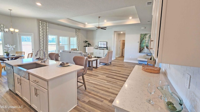 kitchen featuring a center island with sink, pendant lighting, light hardwood / wood-style floors, and white cabinetry