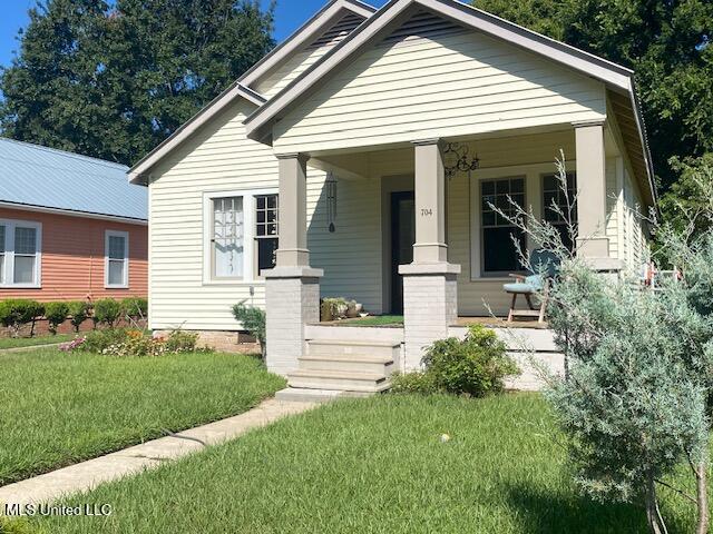 bungalow featuring covered porch and a front yard