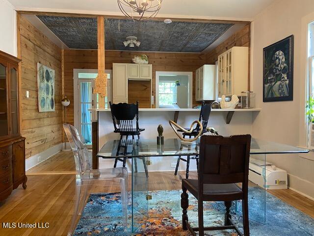 dining room with a chandelier, light hardwood / wood-style floors, and wood walls