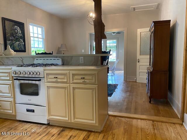 kitchen with gas range gas stove, light hardwood / wood-style flooring, a healthy amount of sunlight, and cream cabinetry