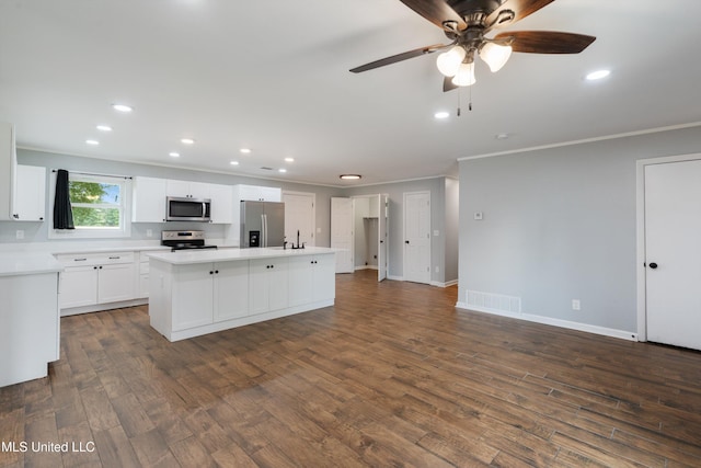 kitchen featuring stainless steel appliances, a sink, ornamental molding, light countertops, and a kitchen island with sink