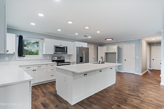 kitchen with appliances with stainless steel finishes, white cabinetry, light countertops, a center island with sink, and dark wood-type flooring