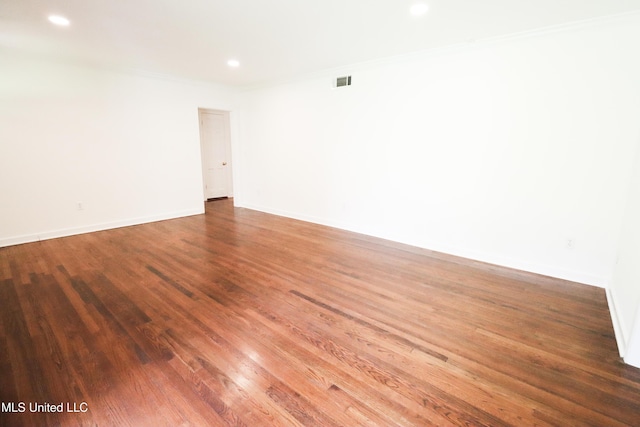 spare room featuring wood finished floors, baseboards, visible vents, recessed lighting, and ornamental molding