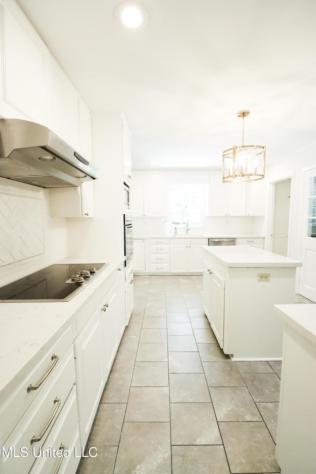 kitchen featuring oven, under cabinet range hood, a kitchen island, light countertops, and black electric stovetop