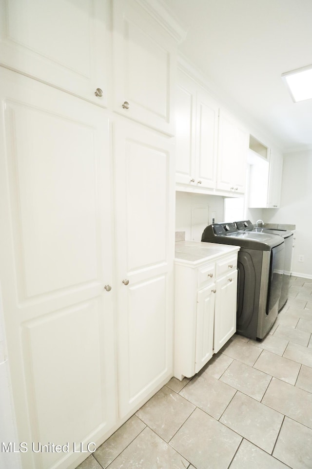 interior space featuring washer and dryer, light tile patterned floors, light countertops, and white cabinetry