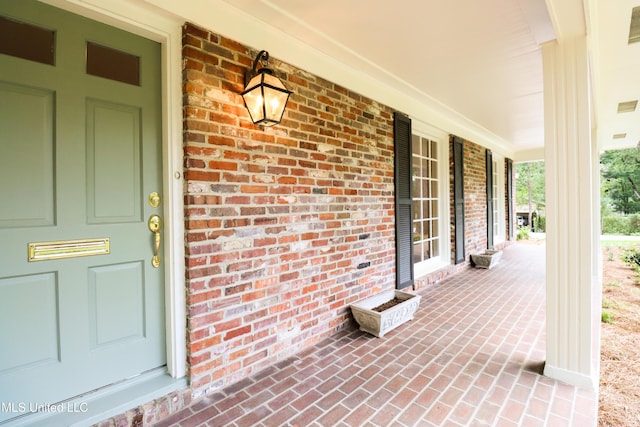 doorway to property with brick siding and covered porch