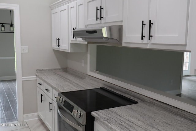 kitchen with stainless steel electric range oven, under cabinet range hood, white cabinets, and baseboards