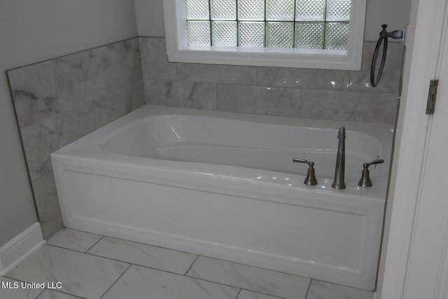 bathroom with a garden tub and baseboards