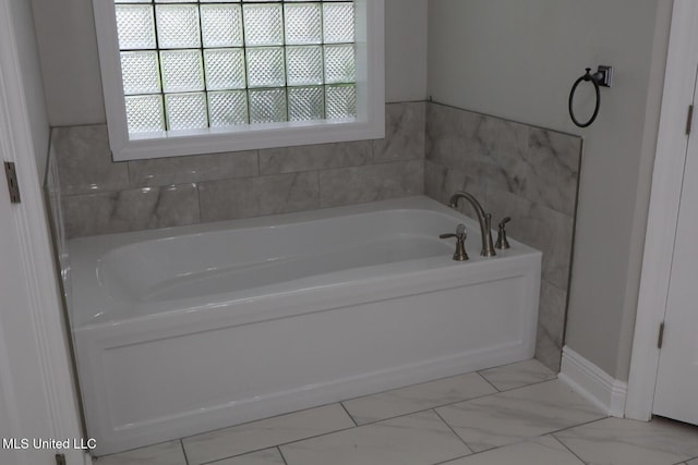 full bathroom with a bath, marble finish flooring, and baseboards