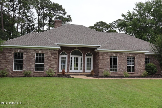 view of front of home with a chimney, a shingled roof, and a front yard