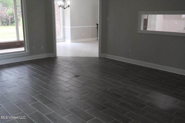 empty room with a chandelier and baseboards