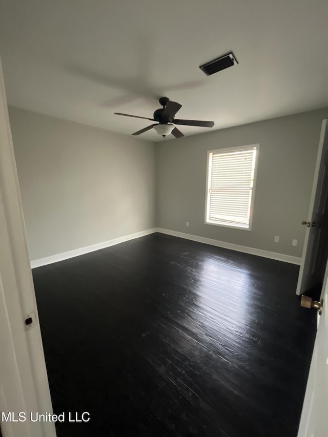 unfurnished room featuring ceiling fan, baseboards, visible vents, and dark wood finished floors