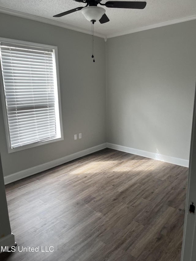 empty room with crown molding, a textured ceiling, baseboards, and wood finished floors