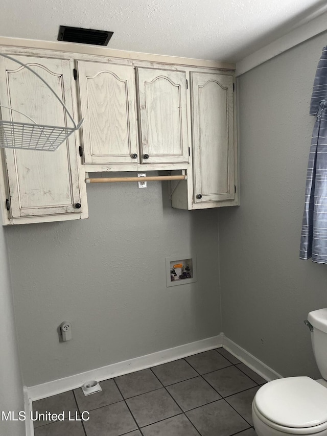 clothes washing area with laundry area, dark tile patterned floors, hookup for a washing machine, and baseboards