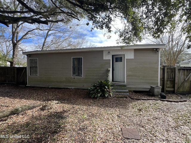 rear view of property with entry steps and fence