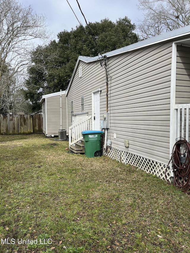 view of side of property featuring central AC, fence, and a lawn