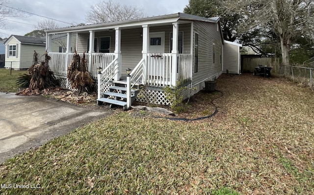 view of front of property with covered porch, fence, and a front yard