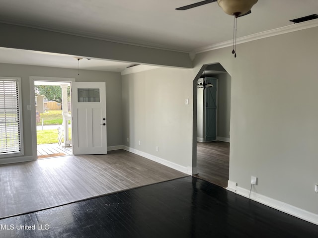 foyer entrance featuring arched walkways, ceiling fan, dark wood-type flooring, baseboards, and crown molding