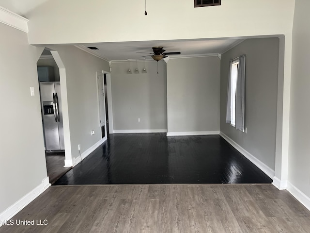 empty room with ceiling fan, arched walkways, crown molding, and wood finished floors